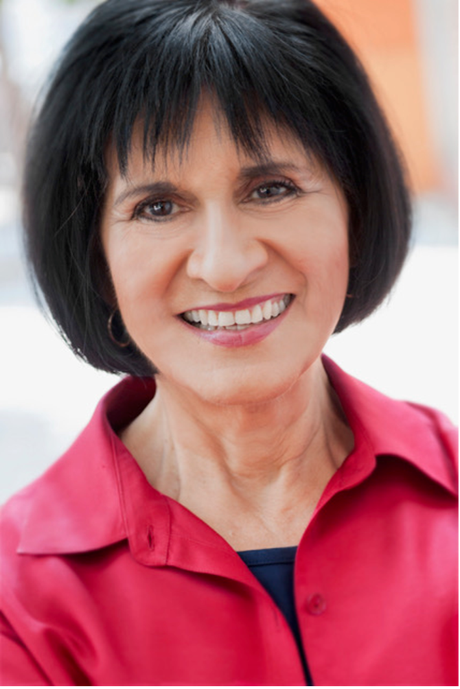 Keynote speaker Irma Herrera smiling and wearing a red blouse in a portrait style picture.