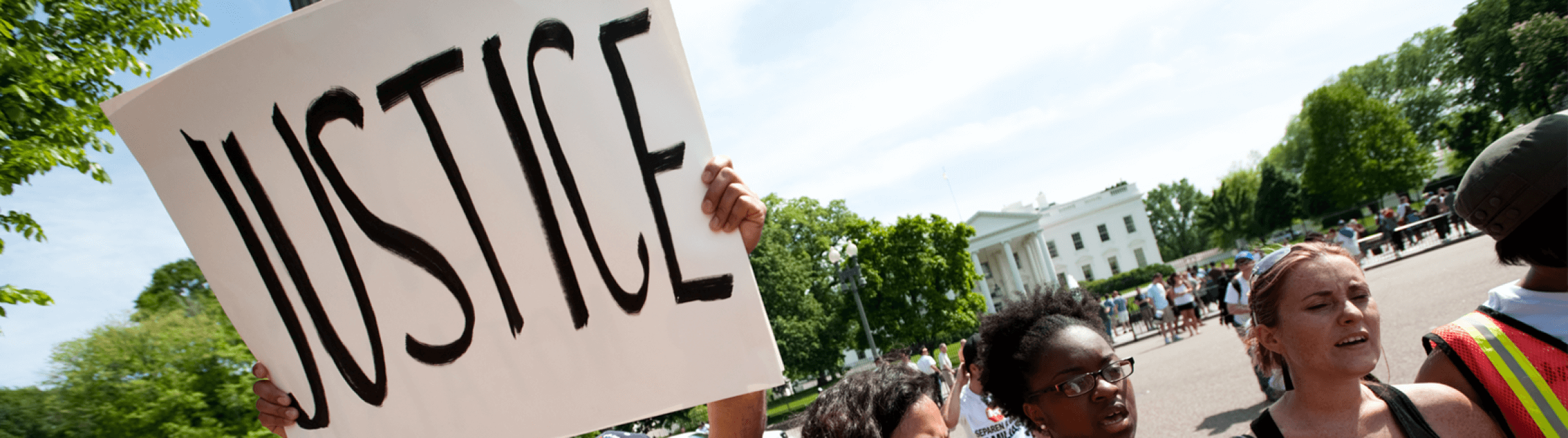 Protestors holding up sign with the word "Justice" on it.