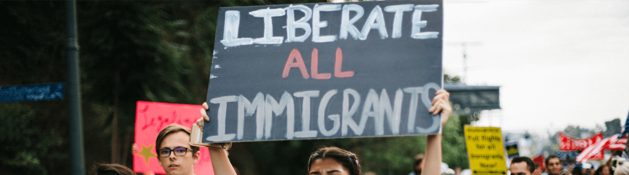 A protester holding a sign that reads "liberate all Immigrants".