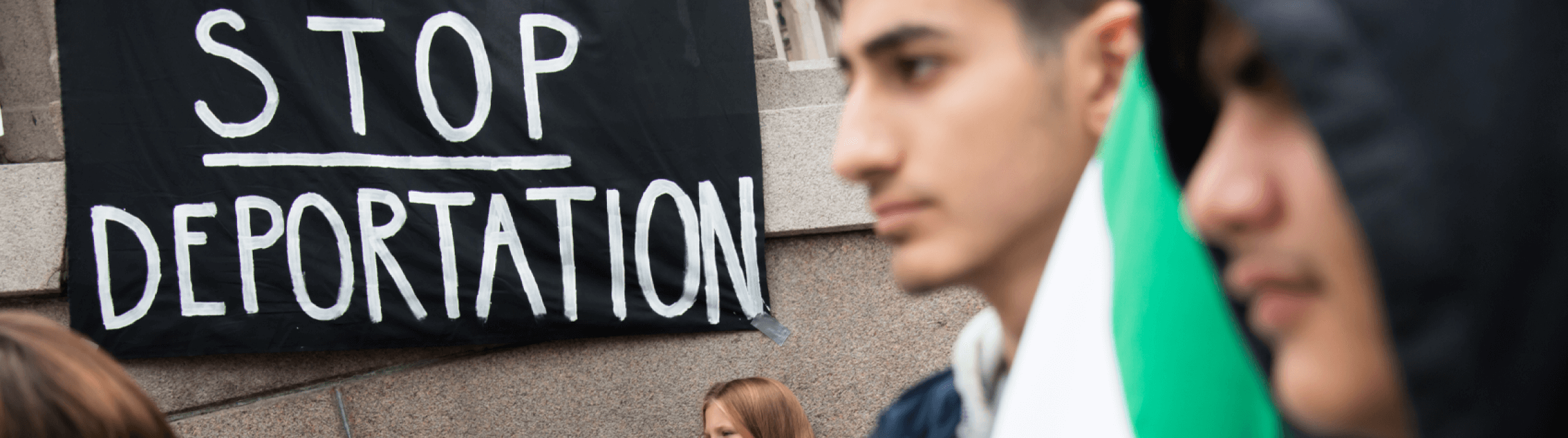 Photo of protestors with a sign saying "stop deportation".