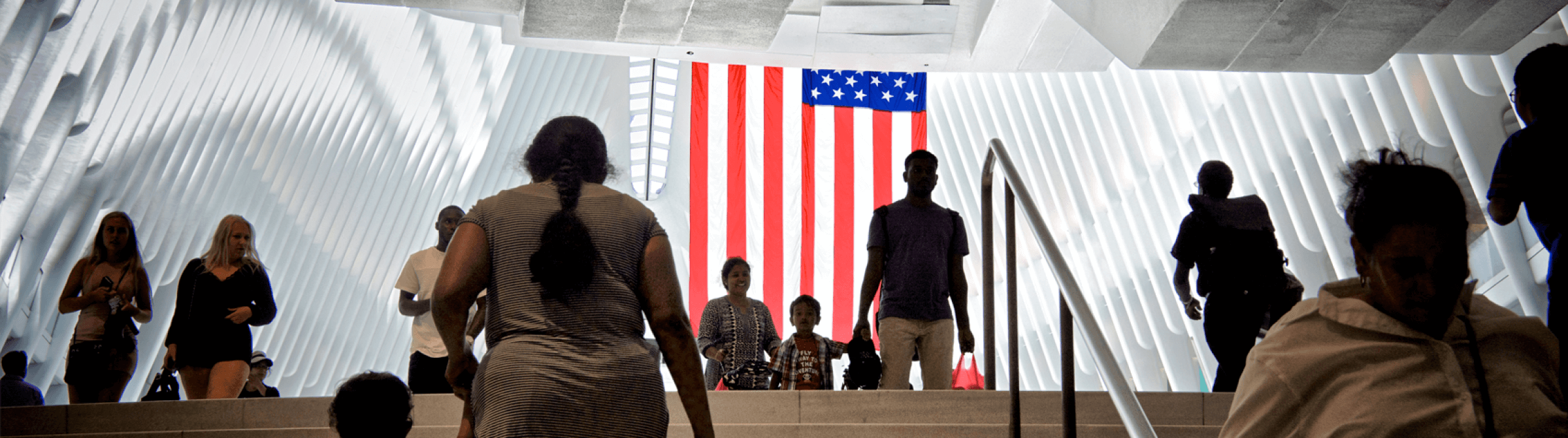 People walking up and down stairs in front of an American flag.