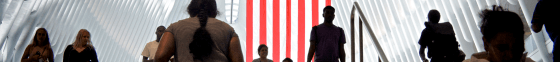 People walking up and down stairs in front of an American flag.