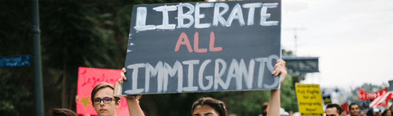 A protester holding a sign that reads "liberate all Immigrants".