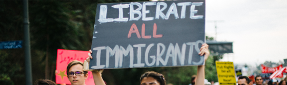 A protester holding a sign that reads "liberate all Immigrants".