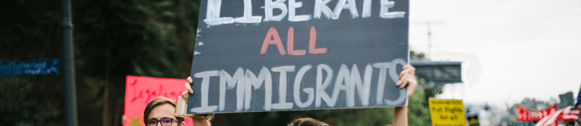 A protester holding a sign that reads "liberate all Immigrants".