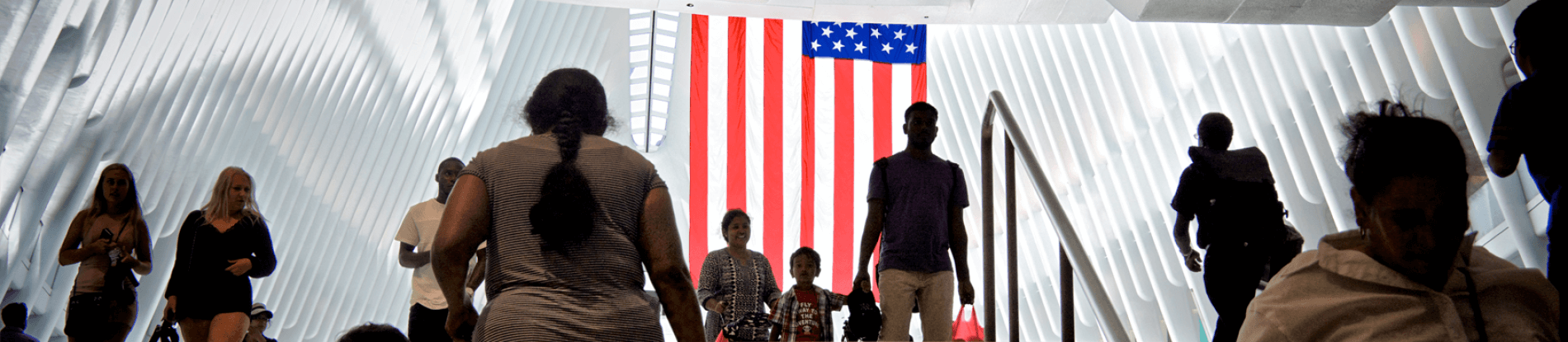 People walking up and down stairs in front of an American flag.